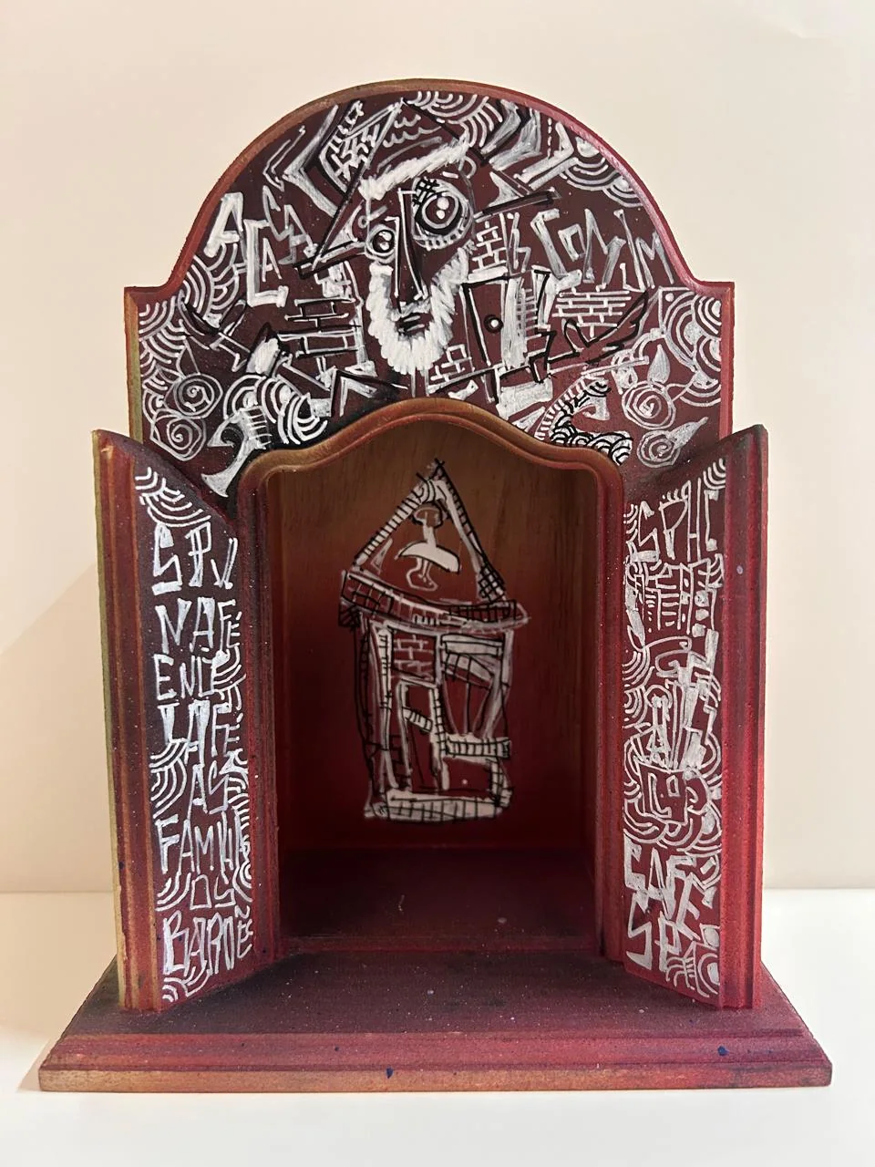 Oratório vermelho com desenho franciscano